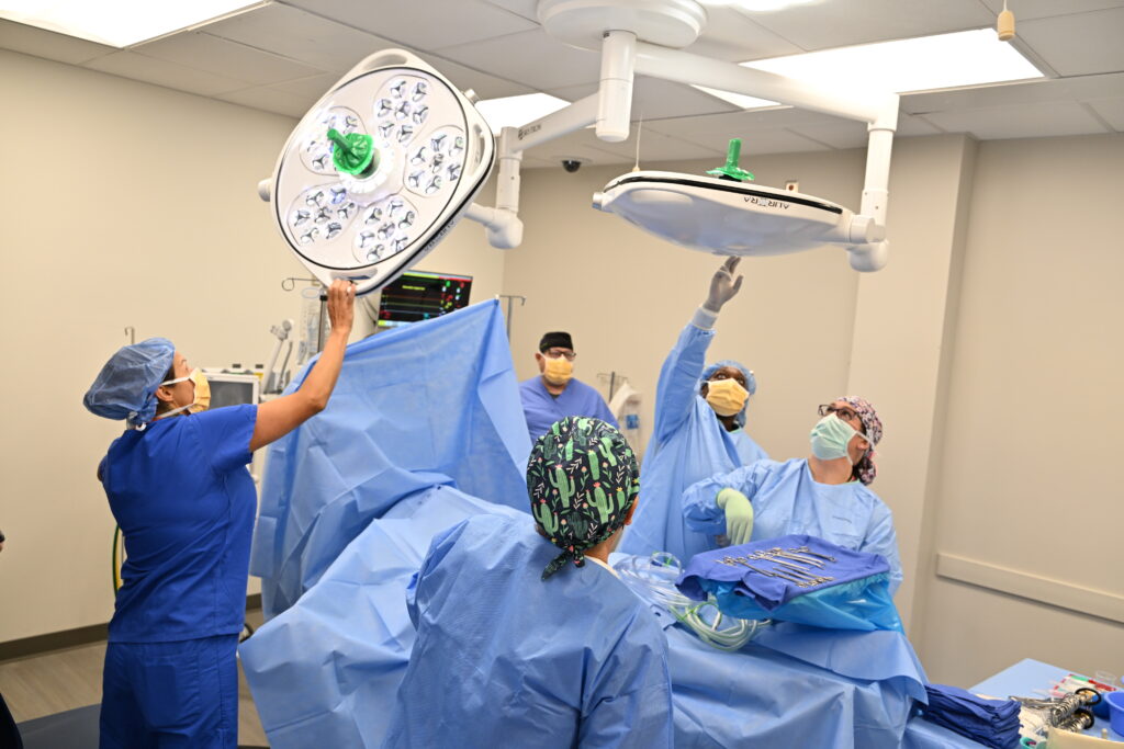 Doctors and nurses wear scrubs while operating on a patient.