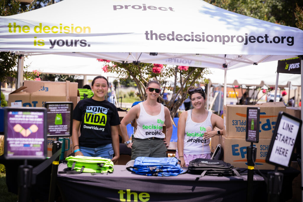 Three women stand at The Decision Project booth at Infinite Legacy's Washington, DC blog party aimed at spreading the critical need for organ, eye and tissue donation.