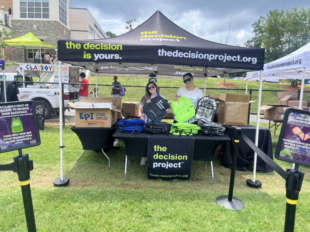 Community outreach staff holds The Decision Project backpacks to hand out to students at one of Infinite Legacy's Block Parties to help raise organ, eye and tissue donation awareness in Maryland, Northern Virginia and Washington, DC.