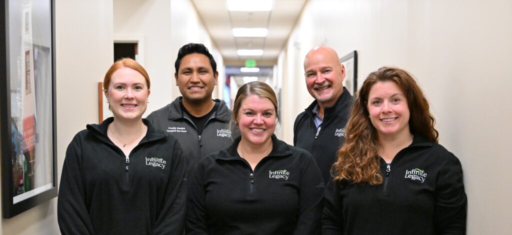 Five Infinite Legacy team members are wearing their branded apparel for a group photo.